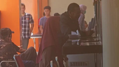 Patients waiting and interacting with reception staff at a hospital counter Stock Footage 340012838