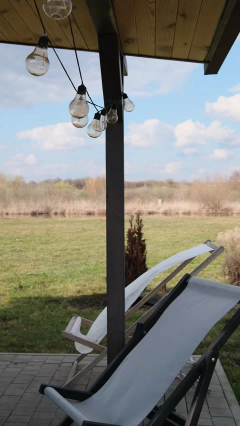 Patio chairs, string lights, serene panorama of green fields Stockbeeldmateriaal 333903700