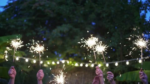 Patio party. The hands of different people hold sparklers. New Year in the Stock Footage 158816618
