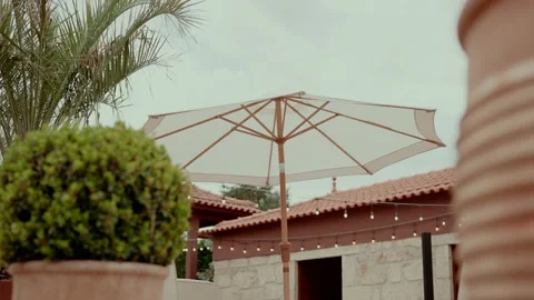 Patio Umbrella and String Lights on a Mediterranean Terrace with Palm and Tiled Stock Footage 338343945
