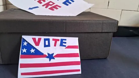 Patriotic envelope with vote text placed beside a ballot drop box Stock Photos