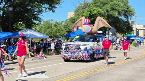 Patriotic parade float with inflatable eagle and marching participants 스톡 동영상 340941694
