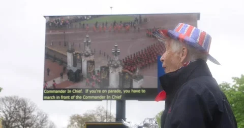 Patriotic spectator watching coronation procession on big outdoor screen Stock Footage 321017628