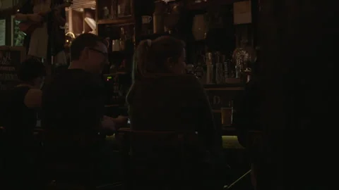 Patrons Sitting at a Dimly Lit Pub Bar Counter Stock Footage 343950247