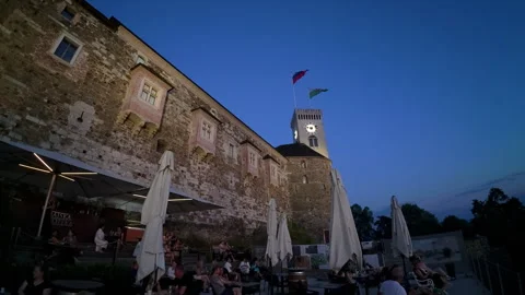 Patrons sitting at an outdoor cafe at the base of the Ljubljana Castle Stock Footage 346242652