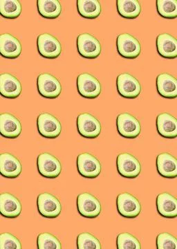 A pattern with avocado halves on an orange background. Stock Photos
