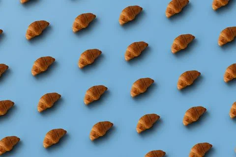 Pattern of baked croissants with a blue background. Delicious pastries Stock Photos