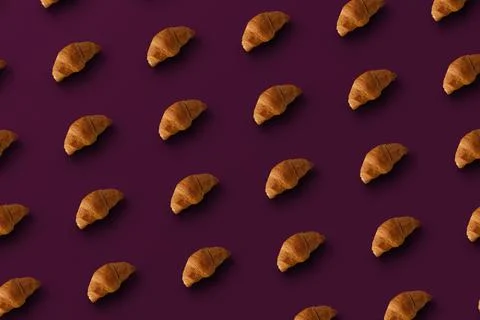 Pattern of baked croissants with purple background. Delicious pastries Stock Photos