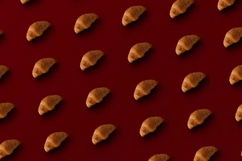 Pattern of baked croissants with a red background. Delicious pastries Stock Photos
