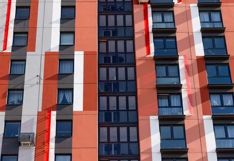 Pattern of balconies and windows on a red and white apartment facade. Moder.. 库存照片