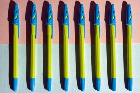 Pattern of ballpoint pens of light green color on a pink-turquoise background 스톡 사진