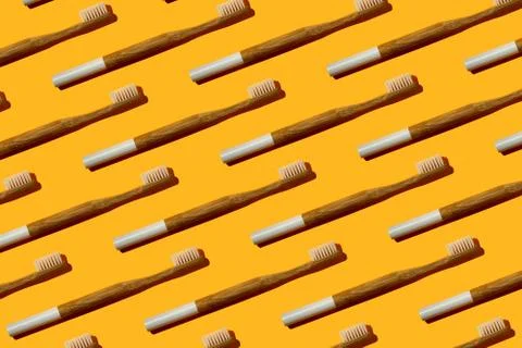 Pattern: bamboo toothbrushes on yellow background Stock Photos