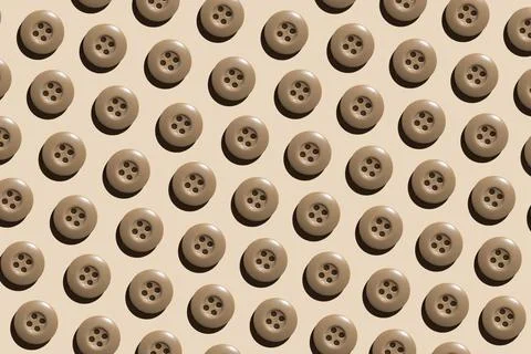 A pattern of beige round plastic buttons on a pastel beige background. The co Stock Photos