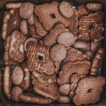 Pattern of biscuits of various shapes inside a square box of reflective tin Stock Photos