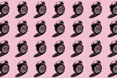 Pattern of black alarm clock on background of pastel pink color. Stock Photos