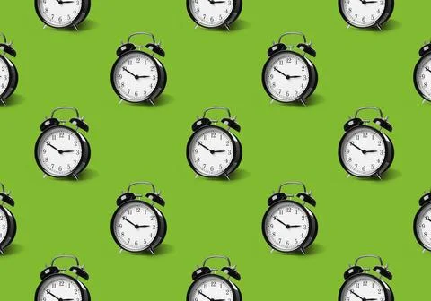 Pattern of black alarm clocks on light green background Foto stock