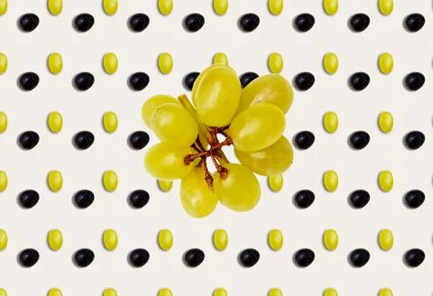 A pattern with black and green grapes in the background and a bunch of green  Foto stock