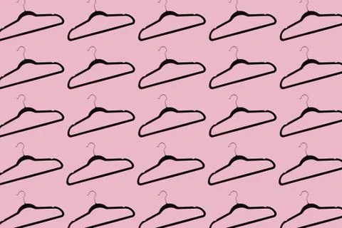Pattern of black hangers isolated on background of pastel pink color. Stock Photos