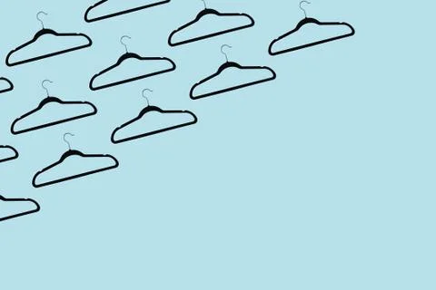 Pattern of black hangers isolated on background of pastel cyan color with space. Stock Photos