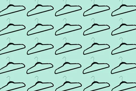 Pattern of black hangers isolated on background of aqua menthe color. Stock Photos