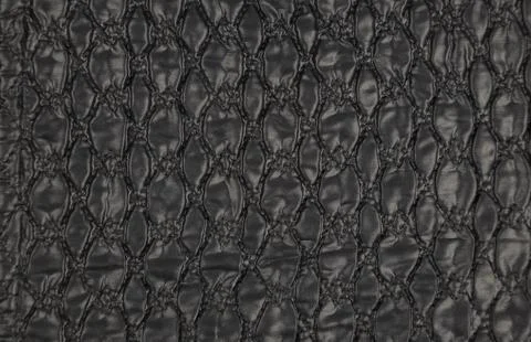 A pattern on a black leather surface. Black leather texture background close-up. Stock Photos