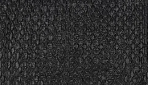 A pattern on a black leather surface. Black leather texture background. Stock Photos