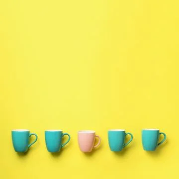 Pattern from blue and pink cups over yellow background. Square crop. Birthday Stock Photos