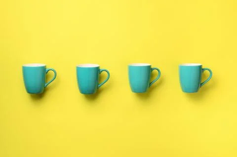Pattern from blue cups over yellow background. Birthday party celebration, baby Stock Photos