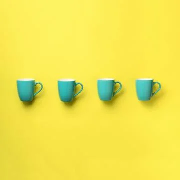 Pattern from blue cups over yellow background. Square crop. Birthday party Stock Photos