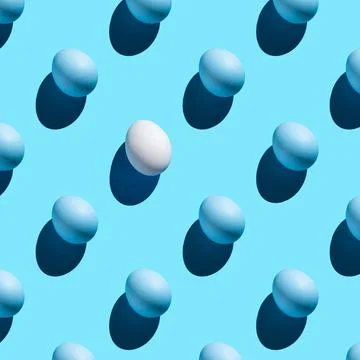 A pattern of blue eggs and one white with a hard shadow on a blue background. Stock Fotos