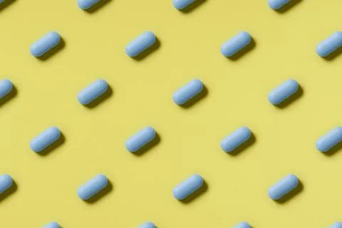 Pattern of blue pills on a yellow background. Hard light. Paper background Stock Photos