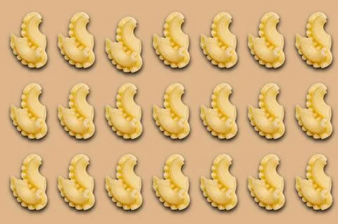 Pattern with boiled macaroni with shadow on a beige background. Stock Photos