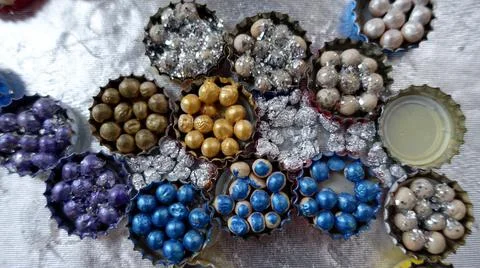 A pattern of bottle caps filled with beads and other decorations Stock Photos