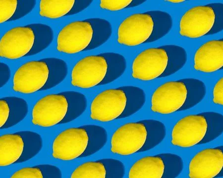 A pattern of bright yellow lemons with a pronounced shadow on a bright blue b Stock Photos