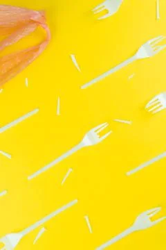 Pattern of broken plastic forks, and bag on a yellow background. Stock Photos