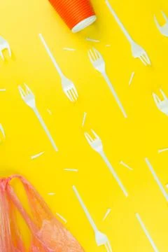 Pattern of broken plastic forks, plastic cup and bag on a yellow background. Stock Photos