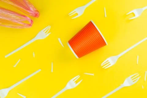 Pattern of broken plastic forks, plastic cup and bag on a yellow background. Stock Photos