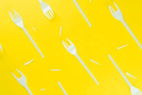 Pattern of broken plastic forks on a yellow background. Stock Photos