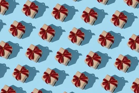 Pattern of brown kraft gift boxes with red velvet bows on a light blue backgr Stock Photos