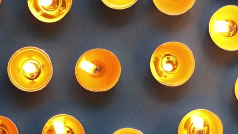 Pattern of burning yellow candles on dark blue, top view, close-up Stock Footage 231050194