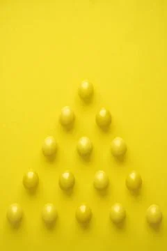 Pattern Of Chicken Eggs In Pyramid Shape Against Yellow Background Stock Photos