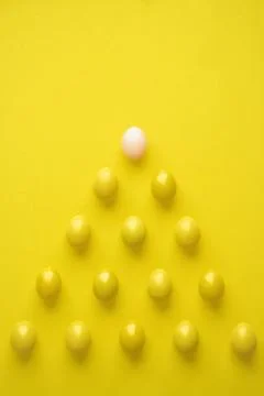 Pattern Of Chicken Eggs In Pyramid Shape Against Yellow Background Foto stock