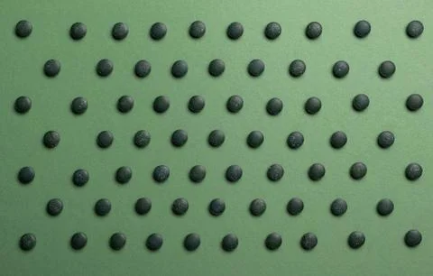 Pattern of Chlorella spirulina tablets on a green background. Stock Photos