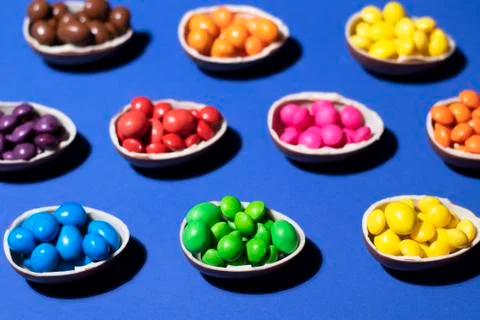 A pattern of chocolate eggs filled with colored jelly on a blue background Stock Photos