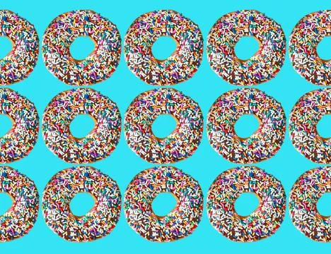 Pattern of chocolate glazed doughnuts with colorful sprinkles on blue background Stock Photos