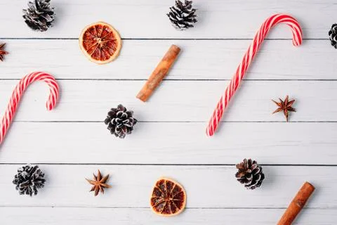 Pattern of christmas candies, pine cones and dried oranges on a white wooden  Stock Photos