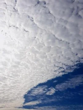 A pattern of clouds covers the sky, illuminated by bright sunlight Stock Photos