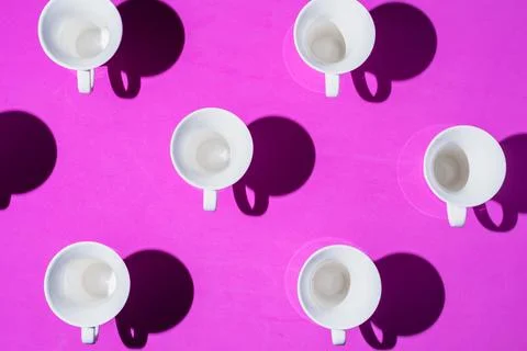 Pattern of coffee cups from a top view casting a hard shadow with the silhoue Stock Photos