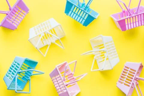 Pattern of colourful plastic shopping baskets on yellow background Stock Photos