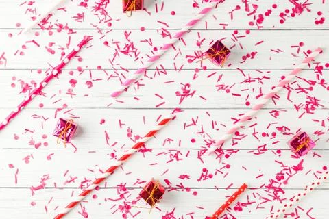 Pattern of confetti, tubes for drinking and small gifts on a white background Stock Photos